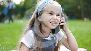 Pretty little child girl having conversation on her mobile phone in summer park
