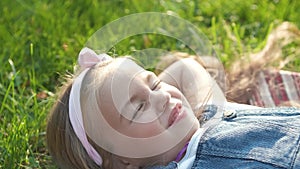 Pretty little child girl laying down on green grass in summer taking a nap.