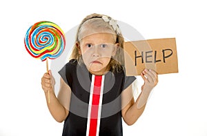 Pretty little child holding lollipop and help sign in children sugar excess photo