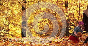 Pretty little girl in black jacket smiles and rejoices in the autumn park with her happy mum