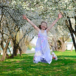 Pretty little girl in blooming apple tree garden on beautiful spring day