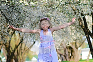 Pretty little girl in blooming apple tree garden on beautiful spring day