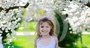 Pretty little girl in blooming apple tree garden on beautiful spring day