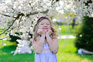 Pretty little girl in blooming apple tree garden on beautiful spring day