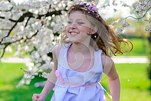 Pretty little girl in blooming apple tree garden on beautiful spring day