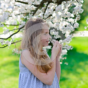 Pretty little girl in blooming apple tree garden on beautiful spring day