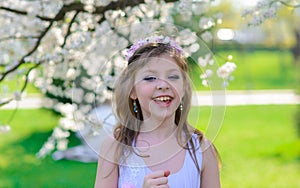 Pretty little girl in blooming apple tree garden on beautiful spring day