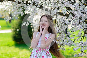 Pretty little girl in blooming apple tree garden on beautiful spring day