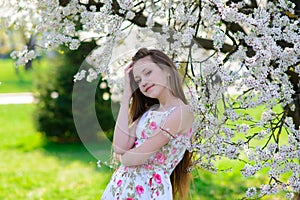 Pretty little girl in blooming apple tree garden on beautiful spring day