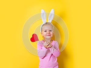 Pretty little girl easter bunny with lollipop or candy on yellow