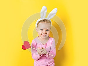 Pretty little girl easter bunny with lollipop or candy on yellow