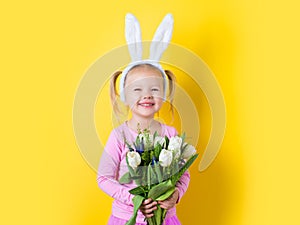 Pretty little girl easter bunny with spring flower on yellow background