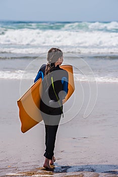 pretty little girl enjoying surfing the waves with a bodyboard during her vacation