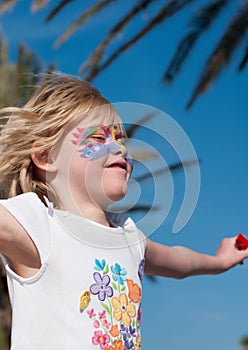 Pretty little girl with facepainting on her face feels exited, and jumping in the air