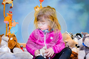 Portrait of a pretty little girl in her room with her stuffed animals