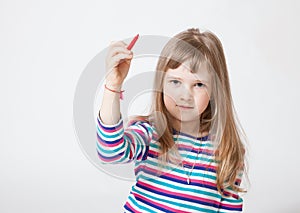 Pretty little girl holding a red felt-tip pen and drawing something