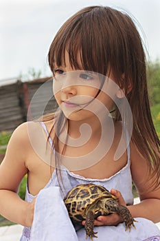 Pretty little girl holding a russian tortoise