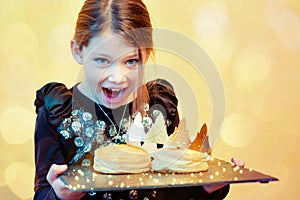 pretty little girl holding a tray with a galette des rois and a crown to celebrate the epiphany