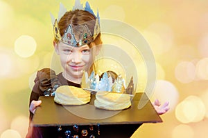 pretty little girl holding a tray with a galette des rois and a crown to celebrate the epiphany