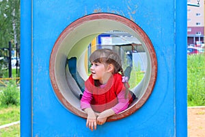 Pretty little girl lies in pipe on playground