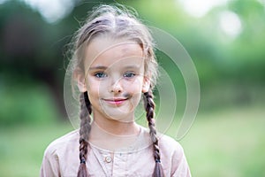 Pretty little girl with long brown hair and beautiful dirty face posing summer nature outdoor. Orphan, child of war, poor