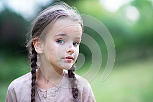 Pretty little girl with long brown hair and beautiful dirty face posing summer nature outdoor. Orphan, child of war, poor