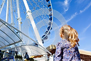 Pretty little girl looks at ferris wheel against a blue sky