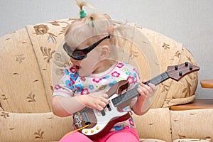 Pretty little girl play on toy guitar.