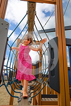 pretty little girl playing climbing in a park portrait of a little girl playing in an amusement park