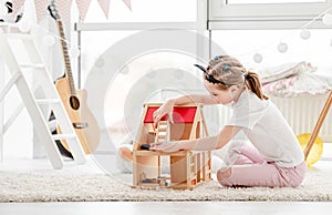 Pretty little girl playing with dollhouse