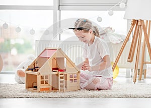 Pretty little girl playing with dollhouse