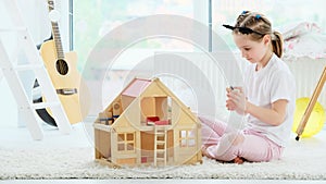 Pretty little girl playing with dollhouse