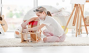 Pretty little girl playing with dollhouse