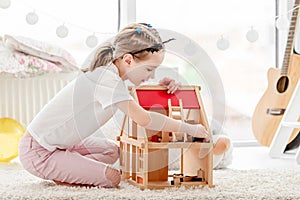 Pretty little girl playing with dollhouse