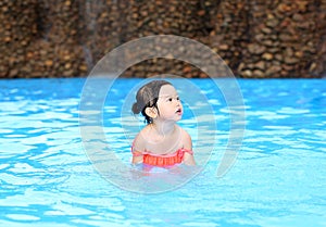 Pretty little girl playing in swimming pool outdoors