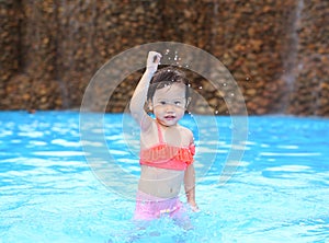 Pretty little girl playing in swimming pool outdoors