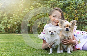 Pretty little girl is posing with two cute dogs outdoors