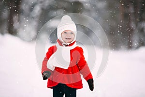 Pretty little girl in red coat in winter forest. Little girl having fun on winter day