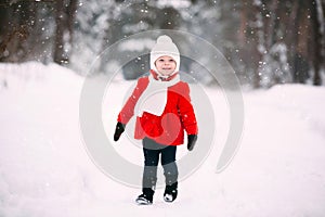 Pretty little girl in red coat in winter forest. Little girl having fun on winter day