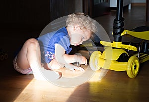 Pretty little girl repairs a wheel of the kick-scooter