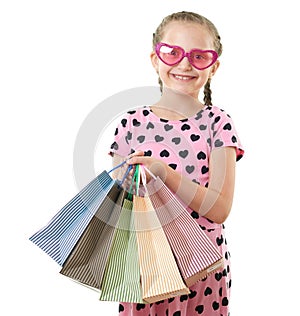 Pretty little girl with shopping bag, studio portrait, dressed in pink with heart shapes, white background