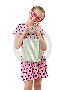 Pretty little girl with shopping bag, studio portrait, dressed in pink with heart shapes, white background