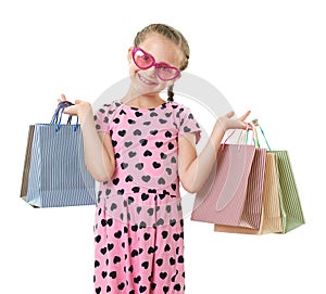 Pretty little girl with shopping bag, studio portrait, dressed in pink with heart shapes, white background