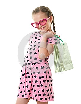 Pretty little girl with shopping bag, studio portrait, dressed in pink with heart shapes, white background