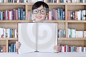 Pretty little girl showing book in library