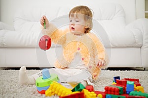 Pretty little girl sits on carpet and holds toy