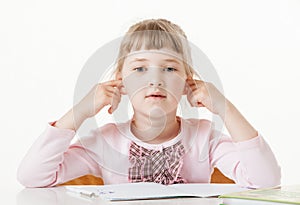 Pretty little girl sitting with closed ears at school desk