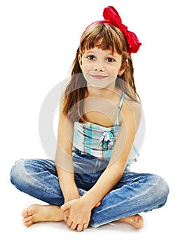 Pretty little girl sitting on the floor in jeans