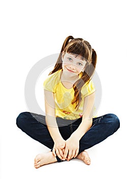 Pretty little girl sitting on the floor in jeans.