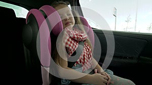 Pretty little girl sleeping in car seat during ride in backseat